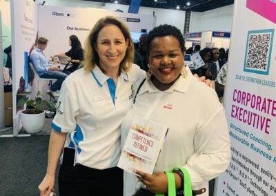 A visitor to Stand C31 with a signed copy of Competence Refined by Dr Elana Siew